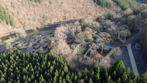 Luftaufnahme vom Ferienpark Hameau de la Semois in Belgien mit Holzhütten und Waldlandschaft.