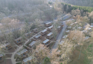 Luchtfoto van vakantiepark Hameau de la Semois in België met huisjes tussen bomen en wandelpaden.