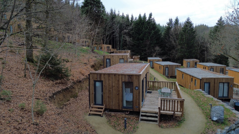 Houten vakantiehuisjes in Hameau de la Semois, een vakantiepark in Belgisch Luxemburg, omringd door bos.