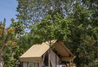 Safari tent Glamping Couple bij Wecamp Santa Cristina in Spanje, omringd door bomen en groene vegetatie.