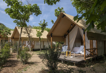 Tenda safari Glamping Couple al Wecamp Santa Cristina in Spagna con veranda esterna e tanto verde.