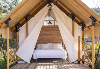 Glamping safari tent voor koppels met houten bed en wit beddengoed bij Wecamp Santa Cristina, Spanje.