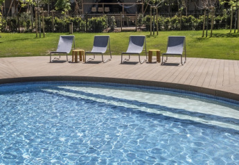 Piscina all'aperto con lettini davanti a tende safari al Glamping Couple presso Wecamp Santa Cristina, Spagna.