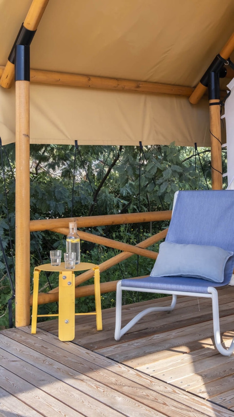 Zonnig terras met een stoel en gele tafel bij Glamping Couple, Wecamp Santa Cristina, Spanje.