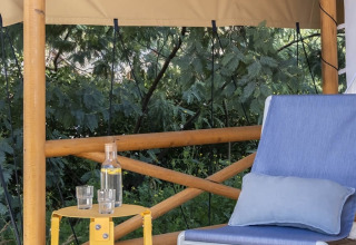Zonnig terras met een stoel en gele tafel bij Glamping Couple, Wecamp Santa Cristina, Spanje.