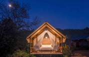 Lit safari tent with a double bed and chairs at night at Wecamp Santa Cristina, Spain, for glamping couples.