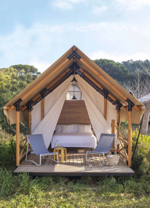 Safaritent met dubbel bed en twee stoelen op het terras midden in de natuur bij Wecamp Santa Cristina, Spanje.