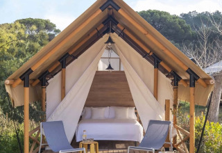 Safaritent met dubbel bed en twee stoelen op het terras midden in de natuur bij Wecamp Santa Cristina, Spanje.