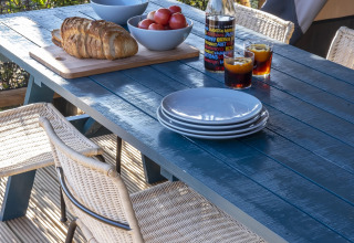 Buitentafel met borden, brood, tomaten en drankjes op het terras van een safaritent.