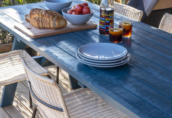 Tavolo all’aperto con piatti, pane, pomodori e bevande su una terrazza di tenda safari.