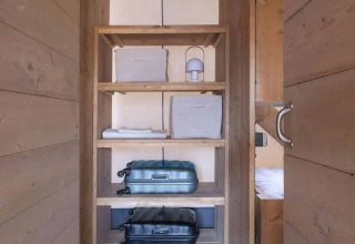 Interieur van Lodge 'Family Duplex' bij Wecamp Santa Cristina, Spanje, met houten planken en koffers.