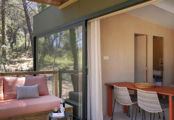 Terraza exterior de la Mobile Home Family en Wecamp Santa Cristina, España, con sofá y zona de comedor.