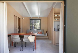 Moderne leefruimte met eettafel en rotan stoelen in Mobile Home Family, Wecamp Santa Cristina, Spanje.