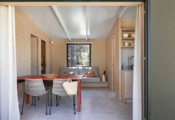 Sala de estar moderna con mesa de comedor y sillas de mimbre en Mobile Home Family, Wecamp Santa Cristina, España.