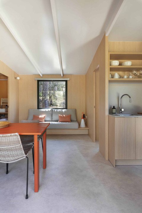 Espace de vie moderne au Mobile Home Family, Wecamp Santa Cristina, avec table orange et canapé gris.