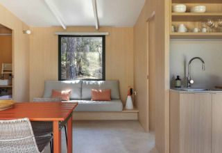 Espace de vie moderne au Mobile Home Family, Wecamp Santa Cristina, avec table orange et canapé gris.