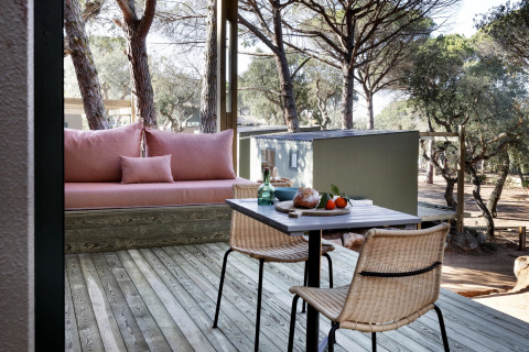Terraza exterior de Mobile home «Couple Plus» en Wecamp Santa Cristina, España, con asientos y vista al bosque.