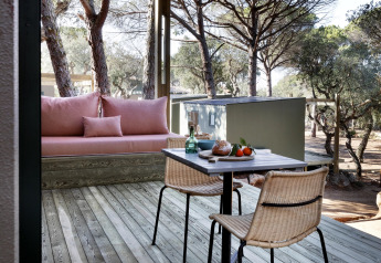 Terrasse du Mobile home «Couple Plus» à Wecamp Santa Cristina, Espagne, avec coin salon et vue sur la forêt.