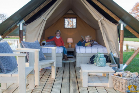 Zwei Kinder im Safari-Zelt Tiny Tent auf dem Campingplatz Waddenzee in den Niederlanden, gemütlich eingerichtet.