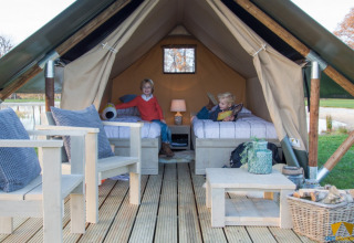 Dos niños en la tienda de safari Tiny Tent en el Camping Waddenzee en los Países Bajos, con interior acogedor.