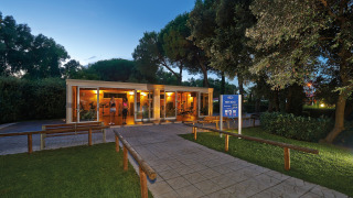 Buitengym bij een glamping-accommodatie, omgeven door bomen, met mensen binnen in de avondschemering.