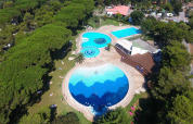 Luftaufnahme eines Glamping-Resorts mit mehreren Pools, Liegewiesen, Bäumen und umgebender Natur.