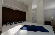 Mobile home bedroom with double bed, striped pillows, brown headboard and bathroom visible through door.