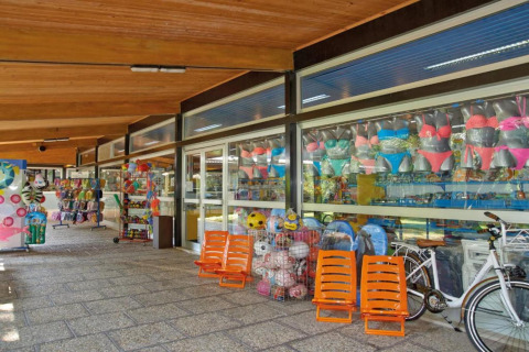 Buitenwinkel bij een stacaravan met badkleding, strandballen, oranje stoelen, speelgoed en een fiets.