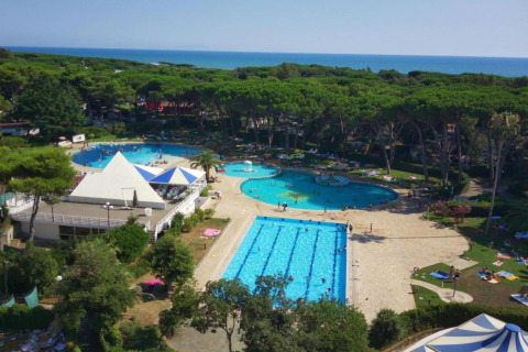 Luchtfoto van Baia Domizia Villaggio Camping C3 in Italië met zwembaden, bos en zee op de achtergrond.