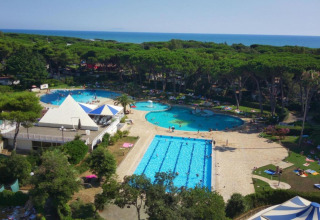 Luchtfoto van Baia Domizia Villaggio Camping C3 in Italië met zwembaden, bos en zee op de achtergrond.