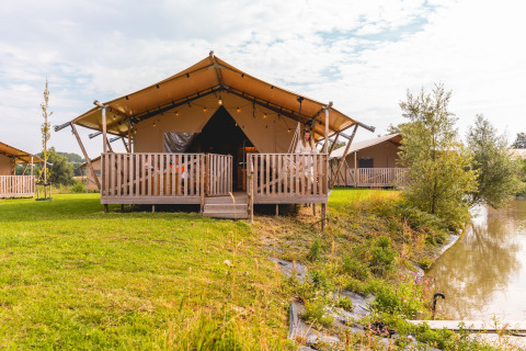 Safari-Zelt im Villa Holiday Park IJsselhof 12 mit Veranda, Seeblick und grüner Landschaft.