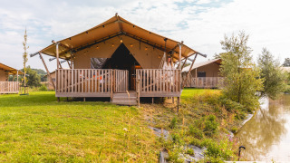 Tente safari au Villa Holiday Park IJsselhof 12 avec terrasse, vue sur le lac et cadre verdoyant.