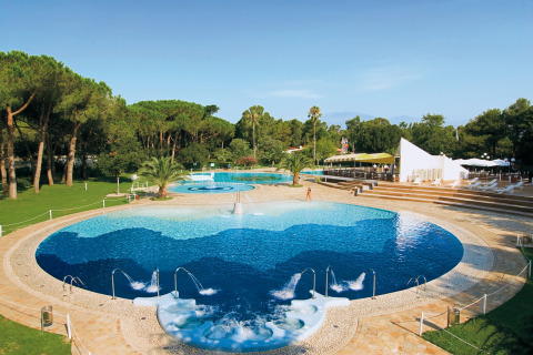 Großer Poolbereich mit Whirlpools und Palmen im Baia Domizia Villaggio Camping I4, Italien, im Grünen.