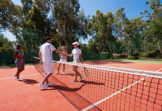 Vier mensen op een tennisbaan in Italië schudden vriendelijk de hand na een dubbelspel in de buitenlucht.
