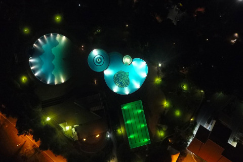 Luchtfoto in de nacht van verlichte zwembaden en camping bij Baia Domizia Villaggio Camping I3 in Italië.