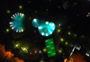 Aerial night view of illuminated swimming pools and campground at Baia Domizia Villaggio Camping I3 in Italy.