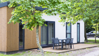Modernes Ferienhaus im Holiday Park Kijkduin mit Holzfassade, Terrasse und Gartenmöbeln im Grünen.
