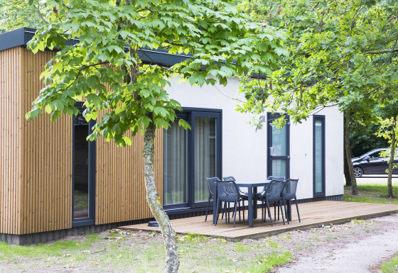 Moderne feriebolig i Holiday Park Kijkduin med træfacade, træterrasse og udendørs spiseplads.