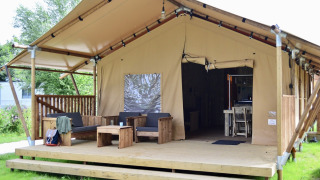 Tente safari Beach Park Vlugtenburg 12 avec terrasse en bois, sièges confortables et entrée ouverte.
