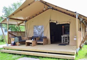 Tente safari Beach Park Vlugtenburg 12 avec terrasse en bois, sièges confortables et entrée ouverte.