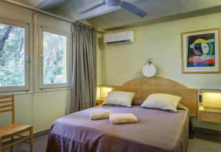 Dormitorio en casa móvil del resort Riva degli Etruschi San Vincenzo, con cama doble y decoración moderna.