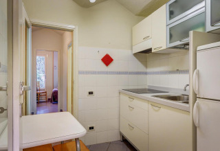 Cocina moderna en una casa móvil con armarios blancos, placa y mesa pequeña, resort en Italia.
