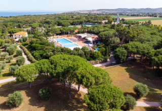 Resort vacacional Riva degli Etruschi San Vincenzo con piscina, árboles frondosos y playa cercana en Italia.