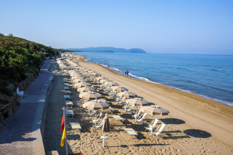 Vista de la playa en el resort Riva degli Etruschi San Vincenzo con tumbonas y sombrillas junto al mar.