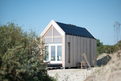 Tiny house de l’Eco Resort Grevelingenstrand, extérieure en bois, panneaux solaires, entourée de nature.
