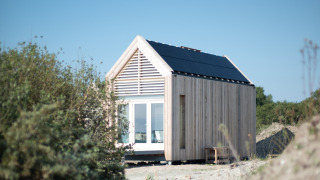 Tiny house bij Eco Resort Grevelingenstrand, met houten buitenkant en zonnepanelen, omringd door natuur.
