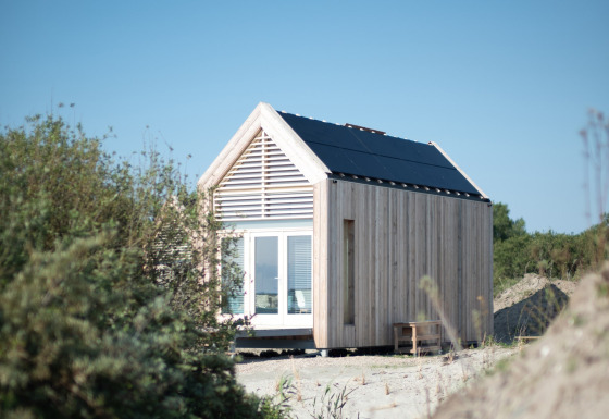 Tiny house de l’Eco Resort Grevelingenstrand, extérieure en bois, panneaux solaires, entourée de nature.