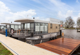 Modernes Hausboot „Elysium“ aus Glas und Holz, vertäut an einem ruhigen Steg in den Niederlanden.