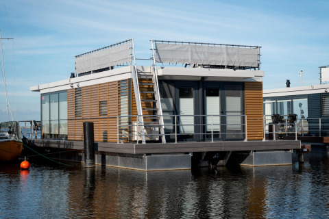 Casa flotante moderna llamada Houseboat «Elysium» con terraza sobre el agua en los Países Bajos.