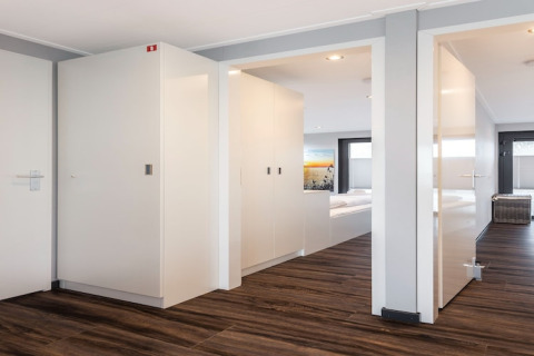Interni moderni della houseboat Elysium nei Paesi Bassi con corridoio, porte bianche e pavimento in legno.